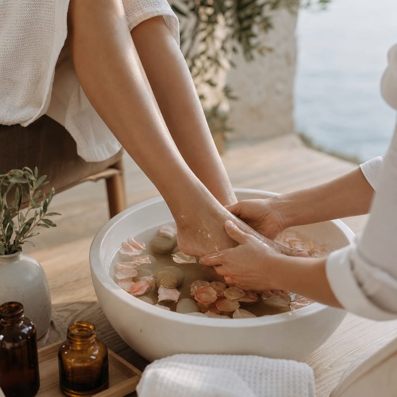 Pieds dans une vasque d'eau tiède aux pétales de rose
